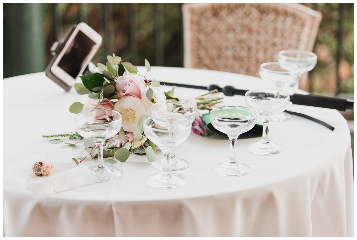Flowers, champagne glasses and a selfie stick laying on a table at the Lakeside Cafe in the St. Louis Zoo, wedding photography by Sandra Grunzinger Photography